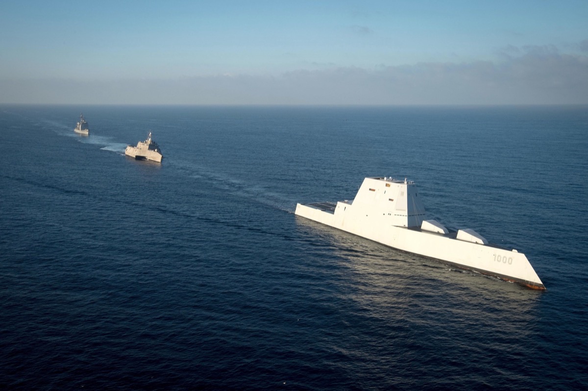 Aerial view of a Zumwalt-class destroyer alongside other Navy warships showing the dramatic size and design differences