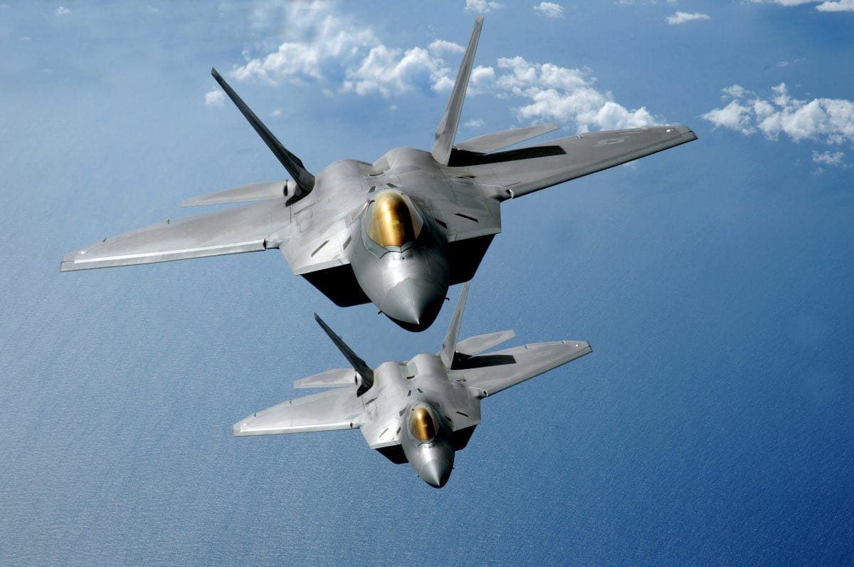 F-22 Raptors in formation flight over mountainous terrain