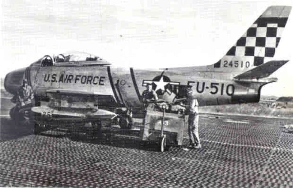 Ground crews prepare an F-86 Sabre with its 51st Fighter Interceptor Wing "Checkertail" for flight during the Korean War.