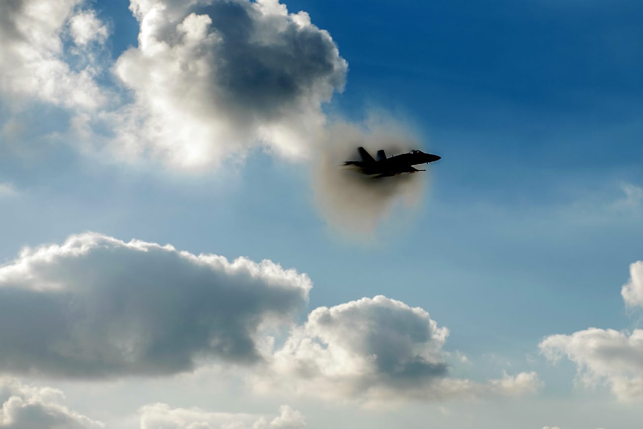 FA-18C Hornet breaks the sound barrier above the flight deck of aircraft carrier