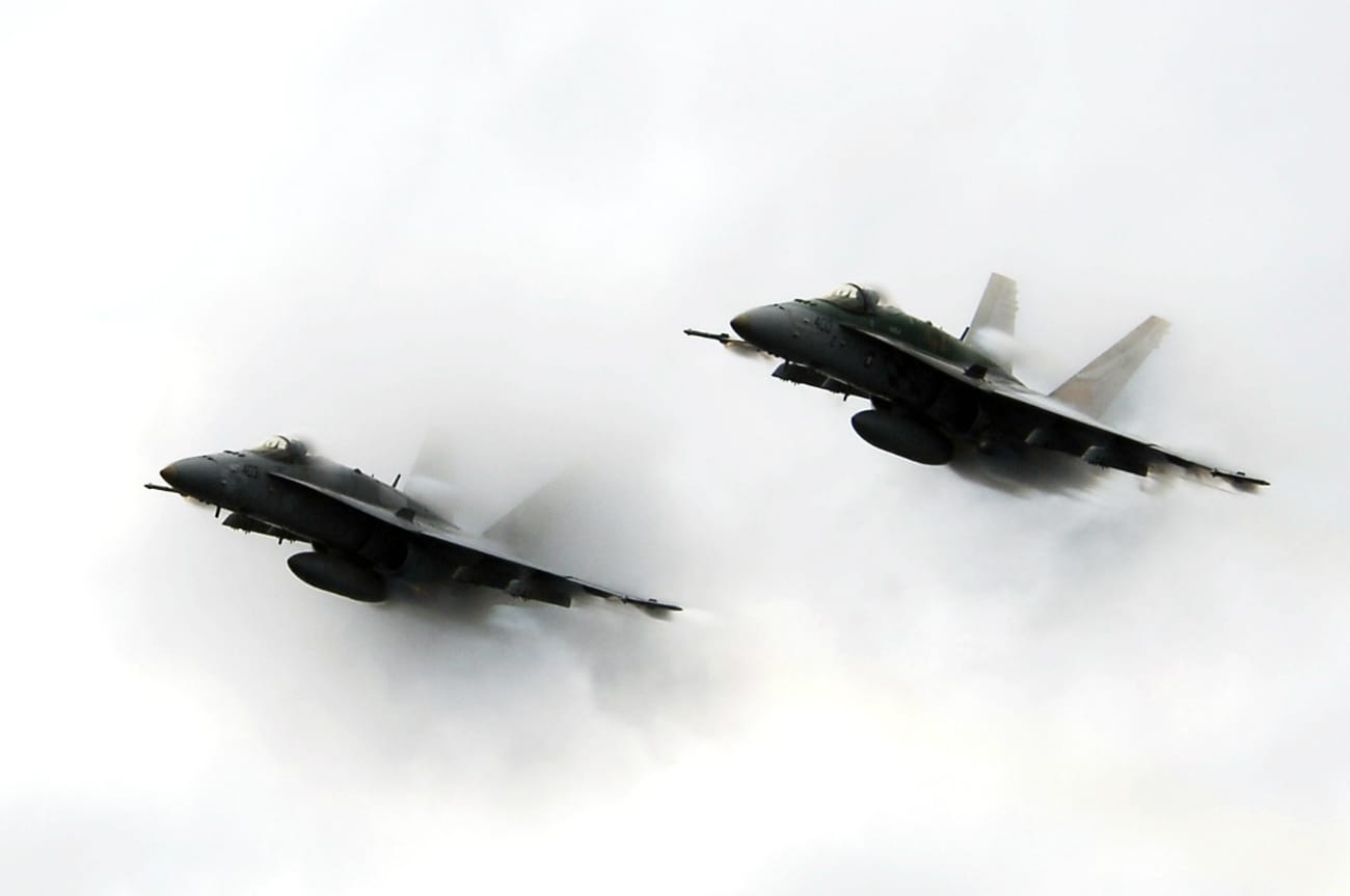 Two FA-18C Hornets punch through a cloud of water vapor while breaking the sound barrier