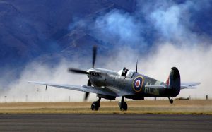 Supermarine Spitfire takes off runway with mountains in the background